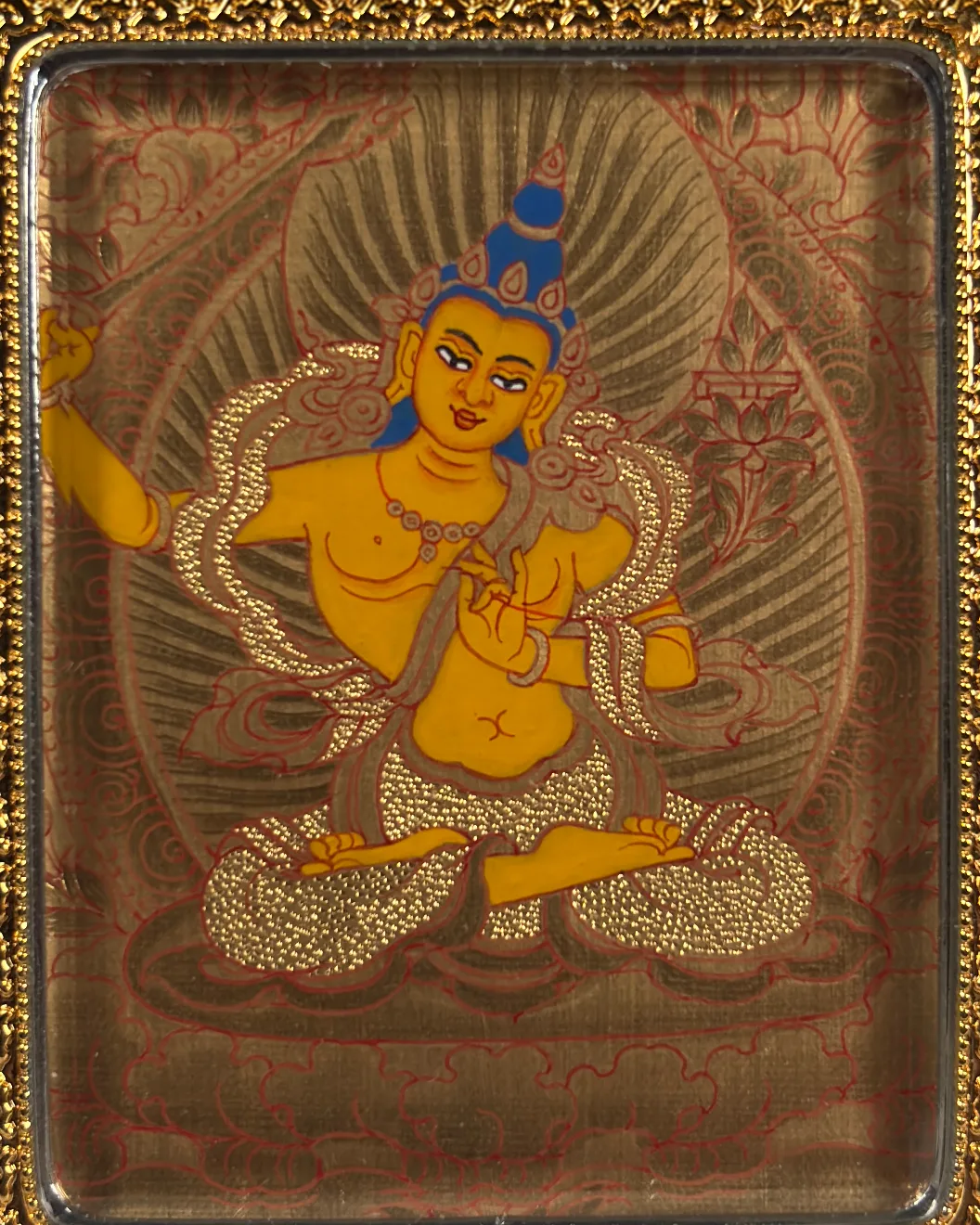 A close detail of a thangka painted with rich mineral colour and gold detail