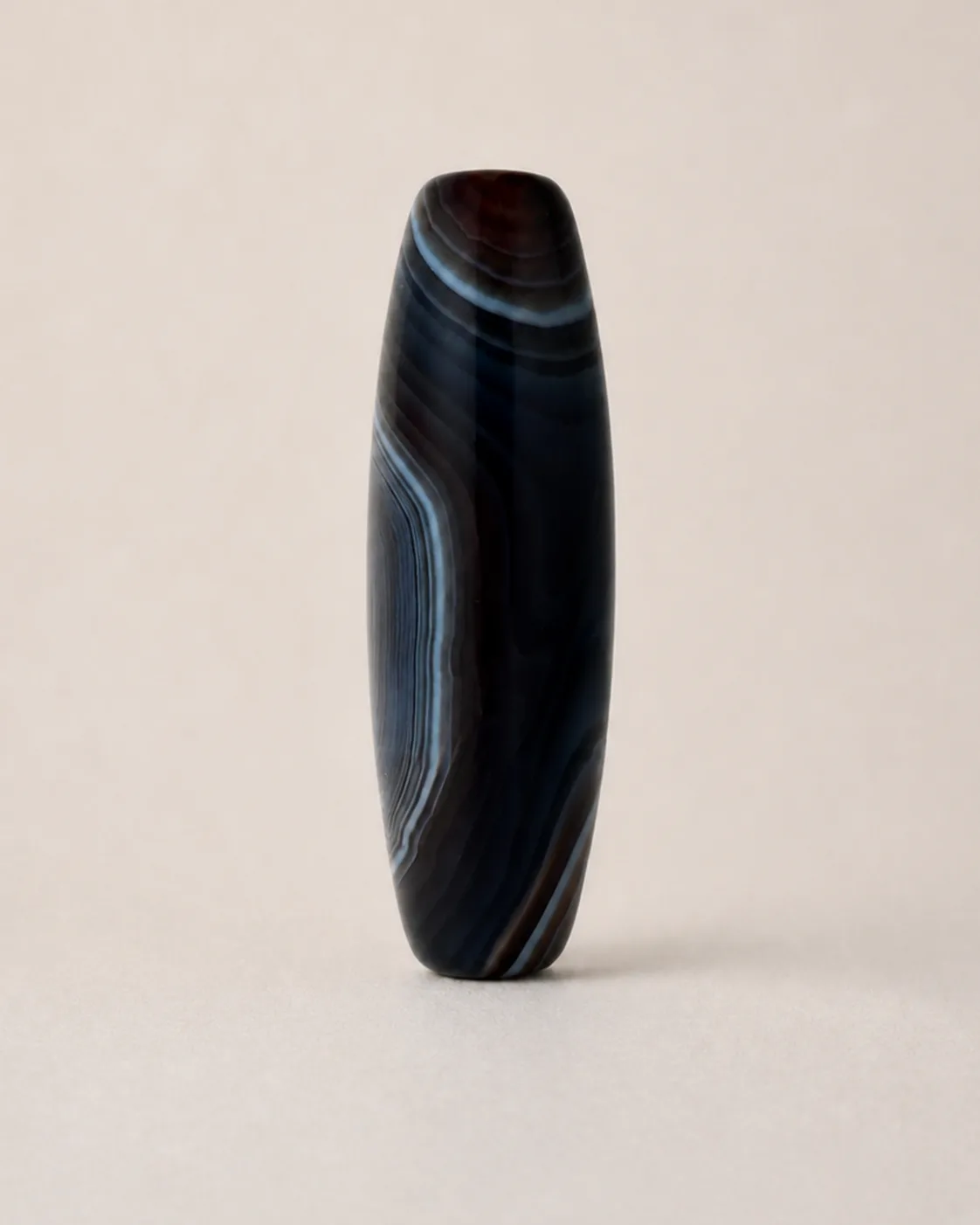 Banded Agate Dzi Bead with asymmetric grey-blue arcs across a dark field — approx. 39.2 × 13.8 mm | Front