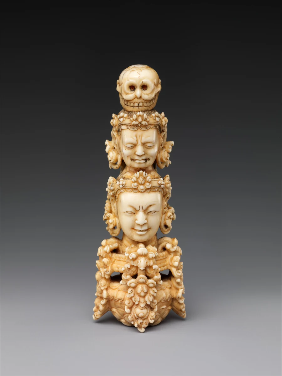 Ivory finial with faces and a skull.