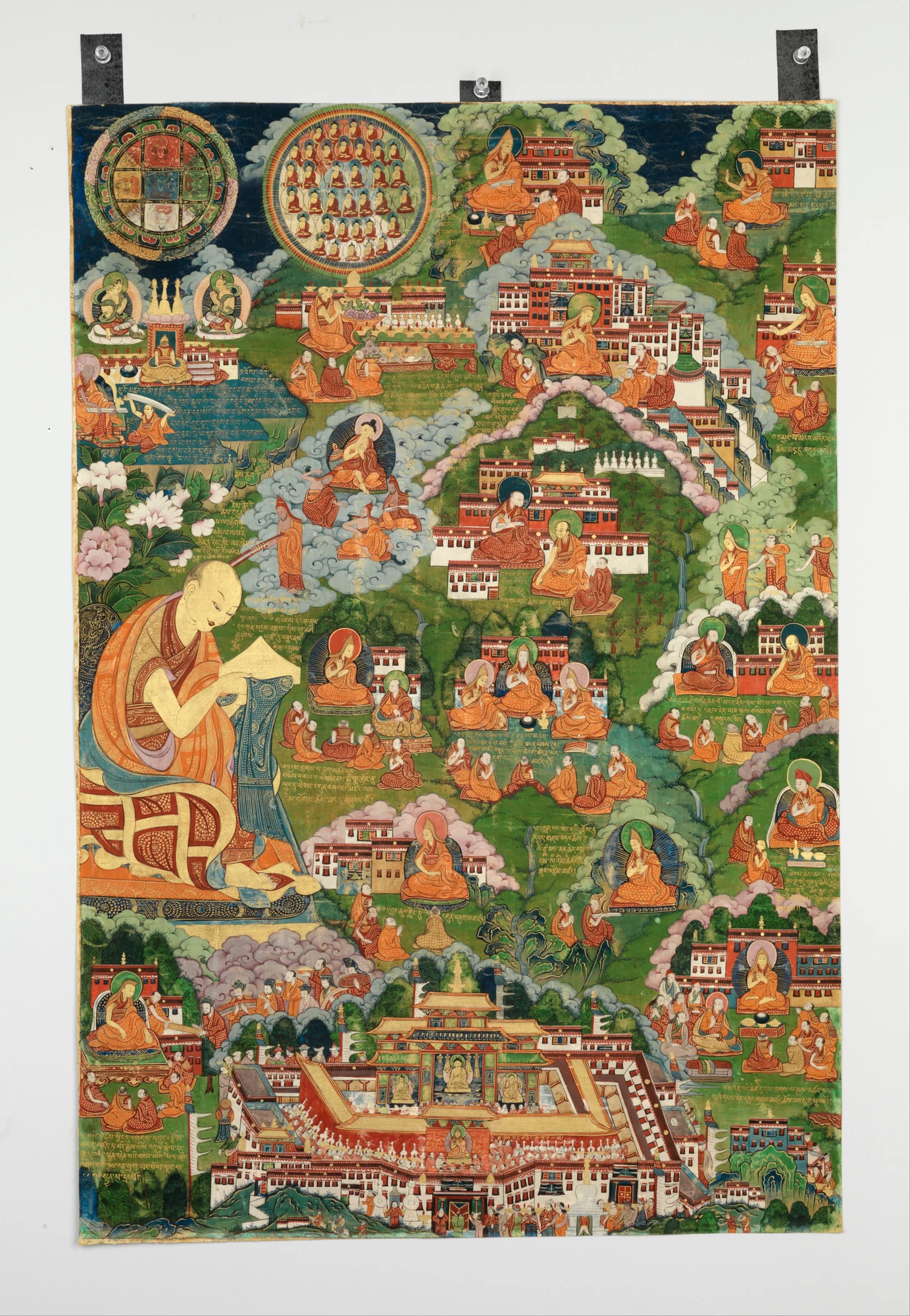Tsongkhapa placed within a green landscape of buildings and cloud bands.