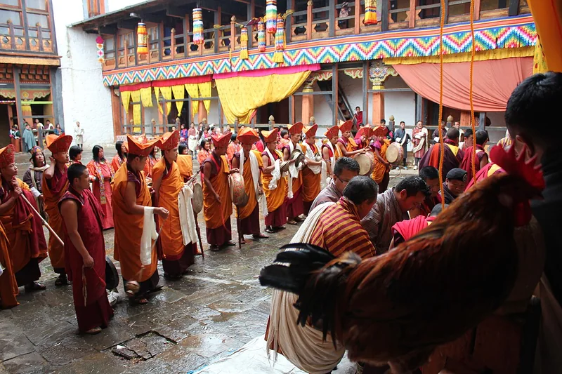 People preparing a thongdrel for raising at Jakar tshechu, with musicians and ropes in the courtyard.