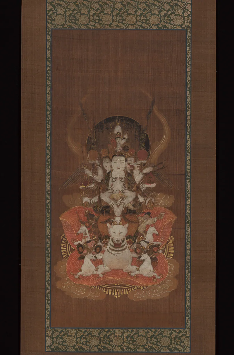 Japanese hanging scroll showing a many-armed, three-faced Dakini figure on a white fox, within a patterned textile mount.