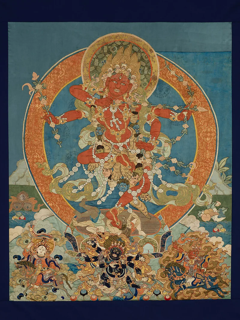 Red four-armed Kurukulla surrounded by patterned fabric forms on a blue textile field.