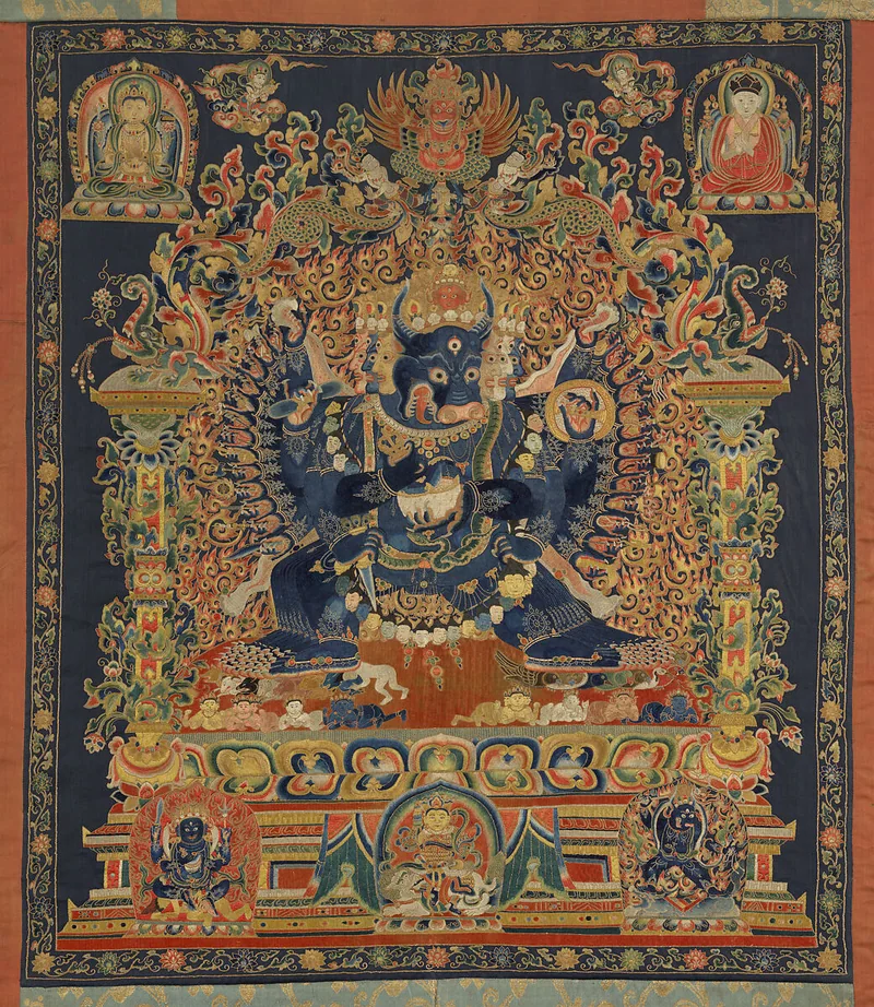 Vajrabhairava embroidery with dark blue central figure, many arms, gold outlines and colourful flame scrolls.