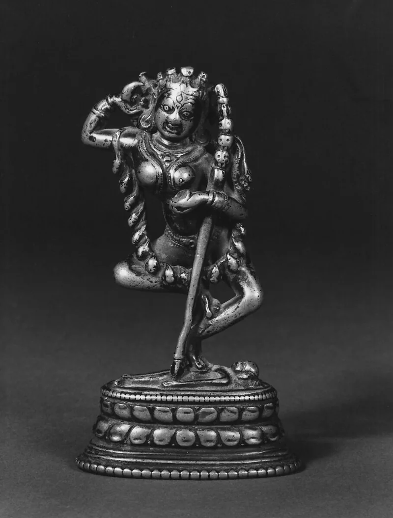 Small copper-alloy Vajravarahi sculpture with a lifted leg and long diagonal staff.
